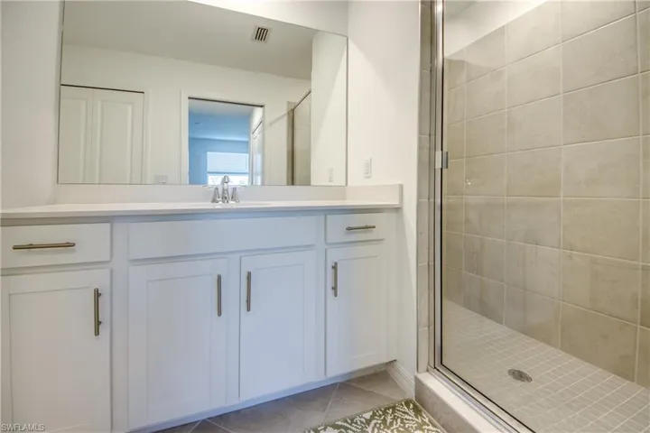 Bathroom featuring a stall shower, light tile patterned flooring, and vanity