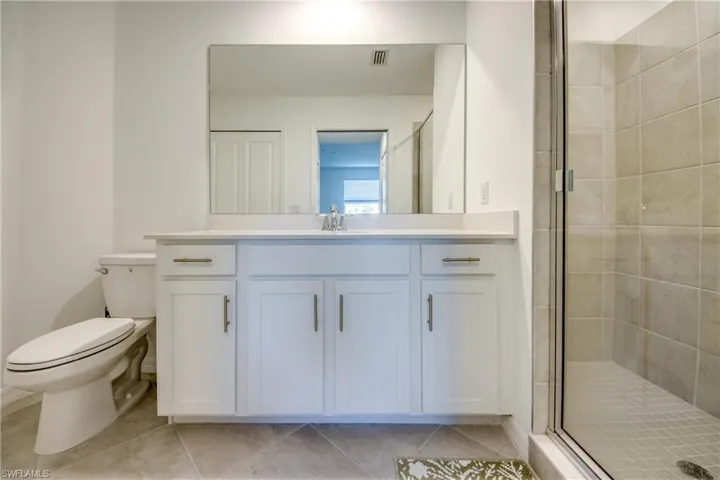 Full bath featuring a shower stall, vanity, and light tile patterned flooring
