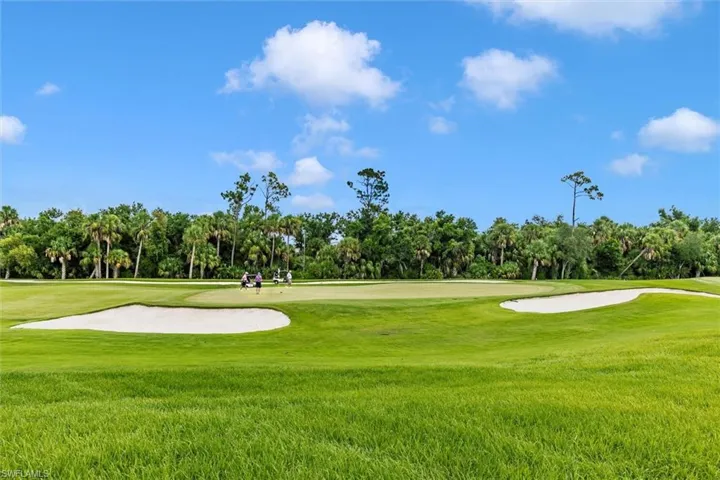 Surrounding community with view of wooded area and view of golf course