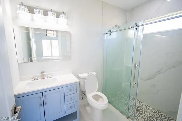 Bathroom with healthy amount of natural light, vanity, and a marble finish shower