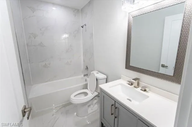 Full bath with marble finish flooring, vanity, and bathtub / shower combination