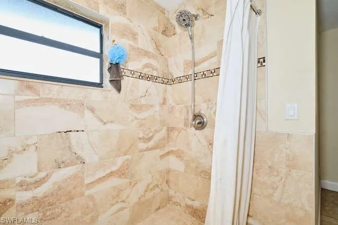 Bathroom with tile walls and a shower with shower curtain