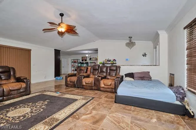 Bedroom with lofted ceiling, ornamental molding, light tile flooring, and ceiling fan