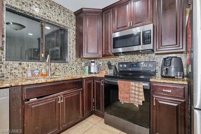 Kitchen featuring backsplash, light tile floors, and range with electric stovetop