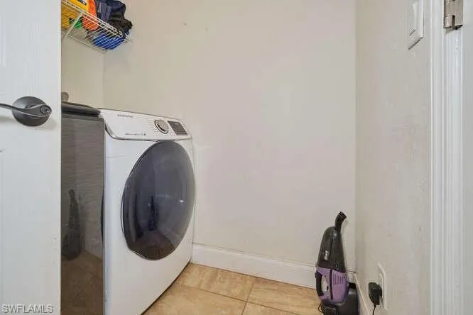 Clothes washing area featuring tile flooring and washer / dryer