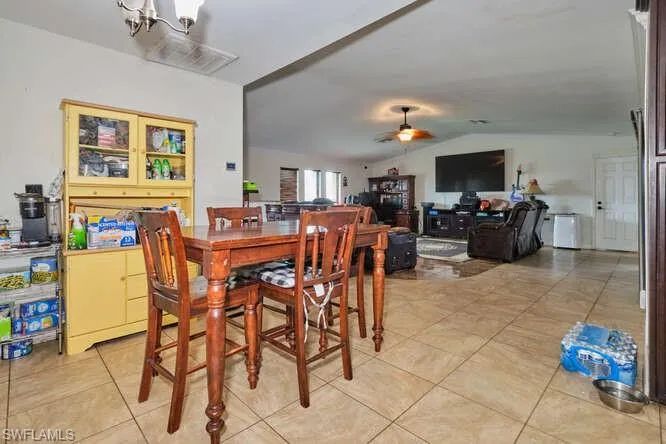 Tiled dining room featuring ceiling fan and vaulted ceiling