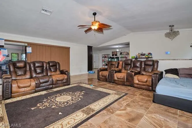 Tiled living room with lofted ceiling, ceiling fan, and crown molding