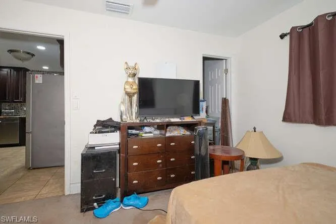 Bedroom featuring stainless steel fridge and light colored carpet