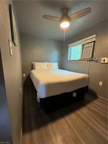 Bedroom with ceiling fan, cooling unit, and hardwood / wood-style floors