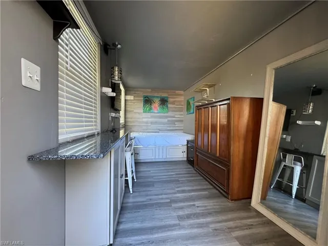 decorative light fixtures, dark hardwood / wood-style floors, and a kitchen bar
