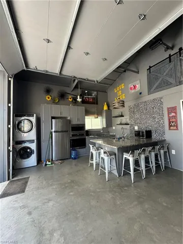 Garage with refrigerator, sink, and stacked washer / drying machine