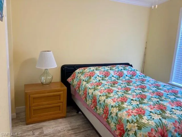 Bedroom featuring wood finished floors and crown molding