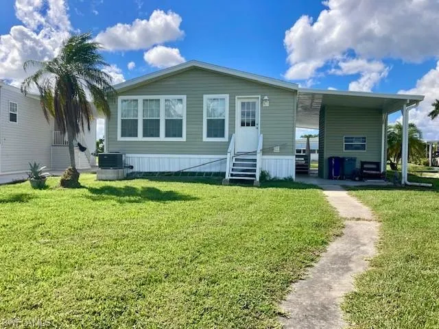 View of front of property featuring a front lawn, a carport, a patio, and entry steps