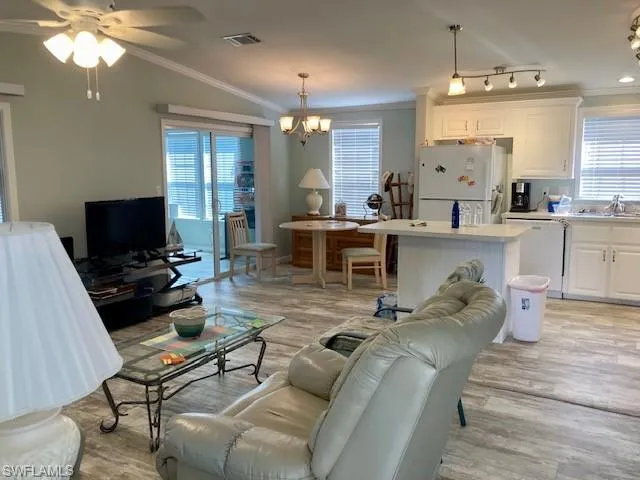 Living area featuring ornamental molding, a ceiling fan, light wood-style floors, and a chandelier