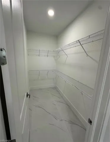 Walk in closet with light marble finish flooring