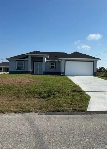 View of front facade featuring a front yard, driveway, stucco siding, and an attached garage