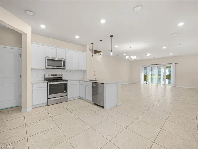 modern kitchen equipped with stainless steel appliances, white cabinetry, and a convenient breakfast bar - perfect for morning coffee or casual meals!