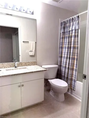 Bathroom with shower / bath combo with shower curtain, vanity, and light tile patterned flooring