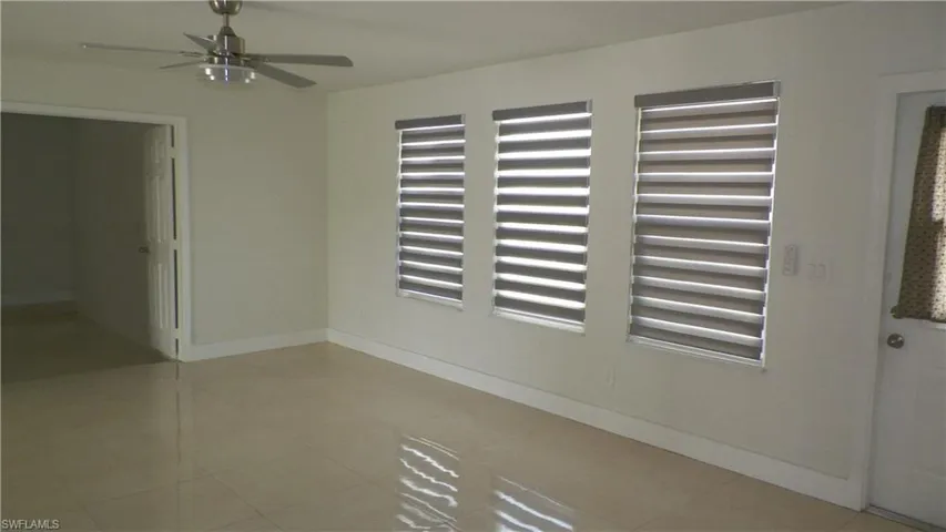 Tiled spare room featuring baseboards and a ceiling fan