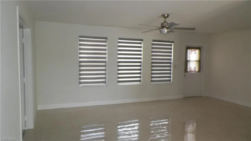 Empty room featuring light tile patterned flooring and ceiling fan