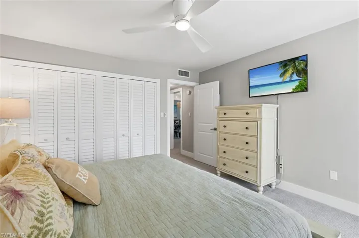 Louvered bifold closet doors, ceiling fan with integrated lighting, wall-mounted television, and neutral wall paint - Virtually Edited Image