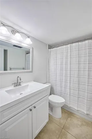 Full bath with visible vents, toilet, shower / bath combo, vanity, and tile patterned floors