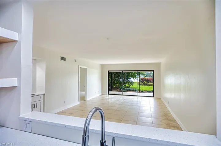 Kitchen with baseboards, visible vents, light stone counters, open floor plan, and light tile patterned flooring