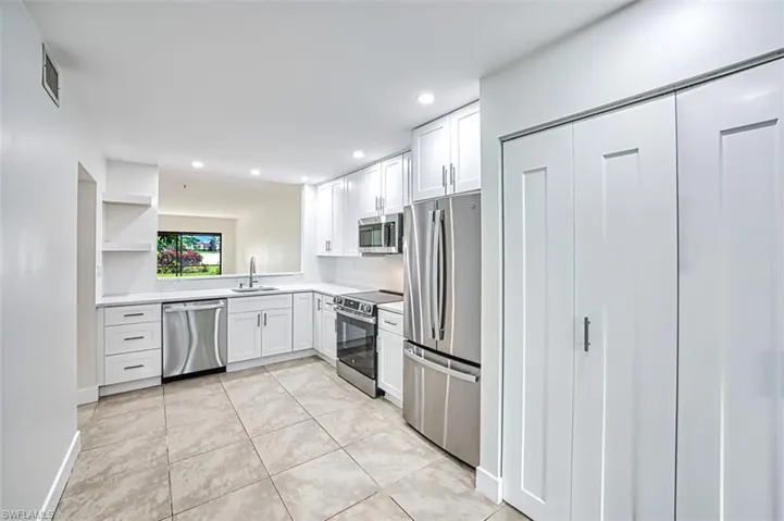 Kitchen with visible vents, white cabinets, stainless steel appliances, light countertops, and a sink