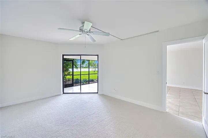 Empty room featuring light colored carpet, a ceiling fan, and baseboards