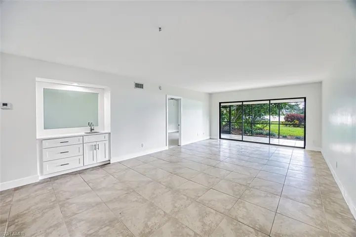 Empty room featuring baseboards, visible vents, and a sink