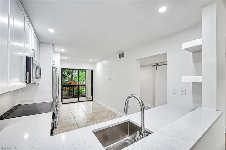 Kitchen featuring stainless steel microwave, light stone counters, a sink, and recessed lighting