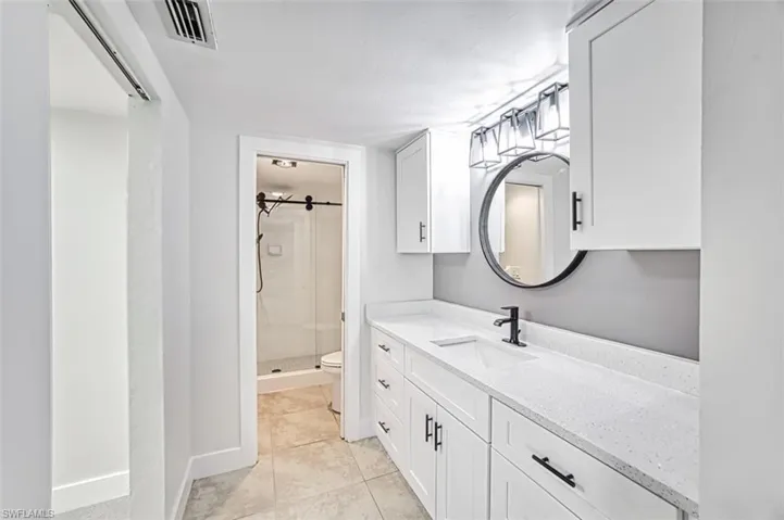 Full bath with toilet, visible vents, vanity, tile patterned floors, and a stall shower