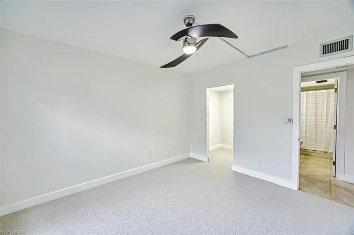 Unfurnished bedroom with light carpet, baseboards, visible vents, and a ceiling fan