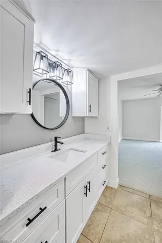 Bathroom with ceiling fan, a textured ceiling, vanity, baseboards, and tile patterned floors