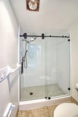 Full bathroom featuring toilet, a shower stall, and tile patterned floors
