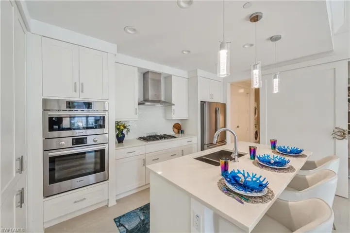 Kitchen featuring white cabinetry, wall chimney exhaust hood, and stainless steel appliances