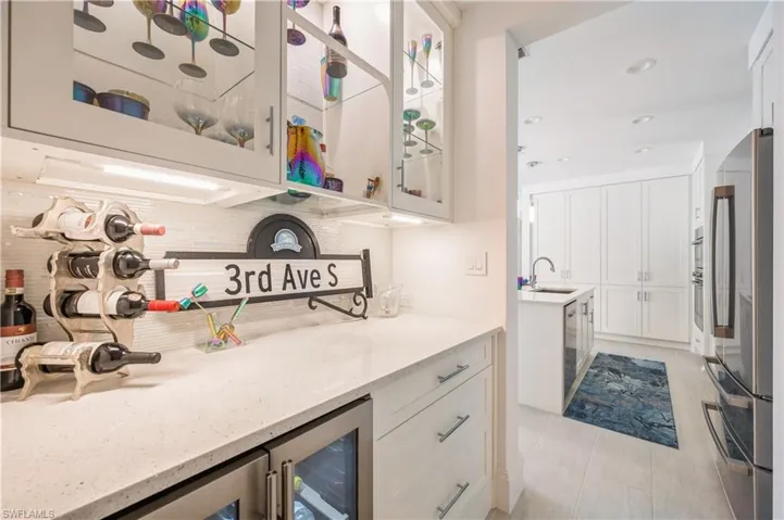 Bar area with lighted upper cabninets, quartz counter top and wine cooler