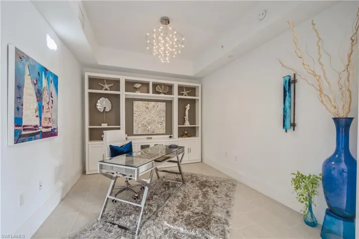 Home office with a chandelier, built in shelves, and a tray ceiling