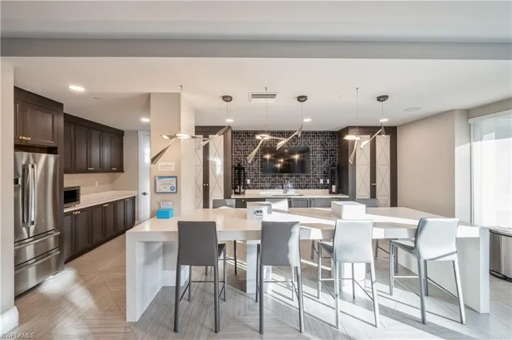 Kitchen featuring appliances with stainless steel finishes, decorative light fixtures, dark brown cabinets, and a large island