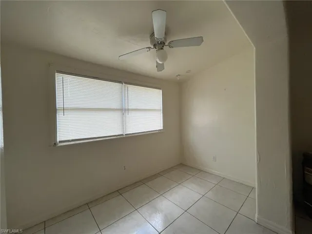 Unfurnished room featuring light tile patterned flooring, baseboards, and a ceiling fan