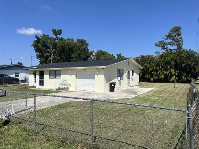 View of front of property with an attached garage, a fenced backyard, driveway, and stucco siding