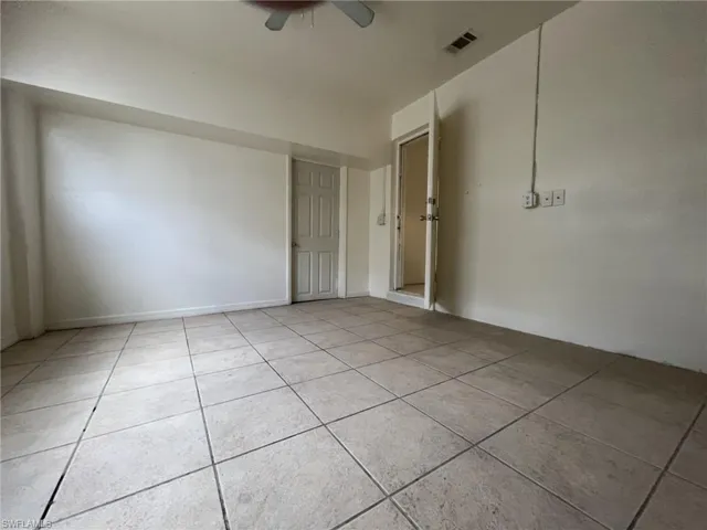 Empty room with light tile patterned floors, visible vents, and a ceiling fan