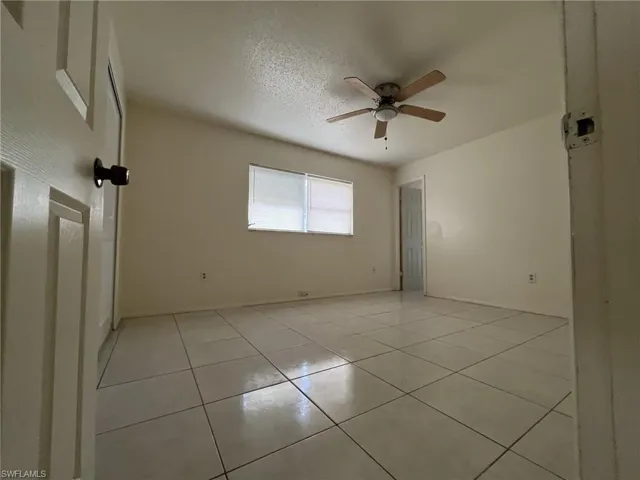 Empty room featuring light tile patterned floors, a textured ceiling, and ceiling fan