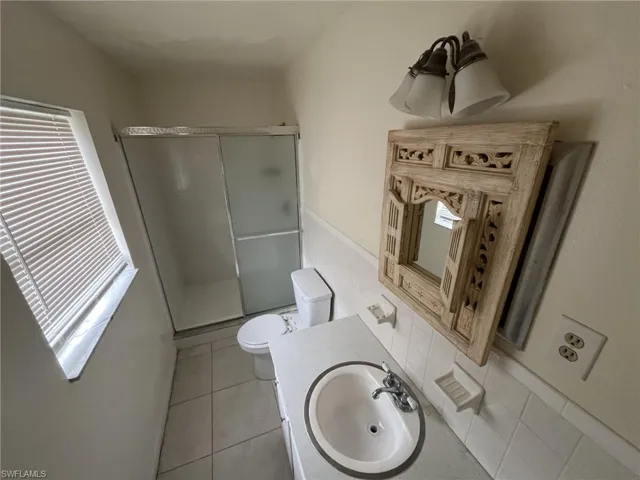 Bathroom with tile patterned floors, toilet, a stall shower, and vanity