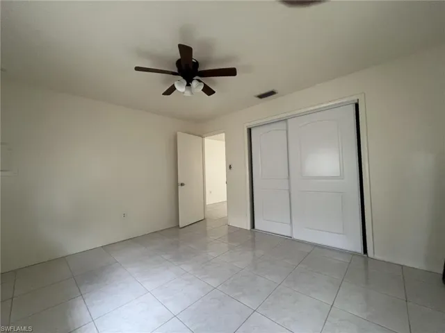 Unfurnished bedroom featuring a ceiling fan, visible vents, and a closet