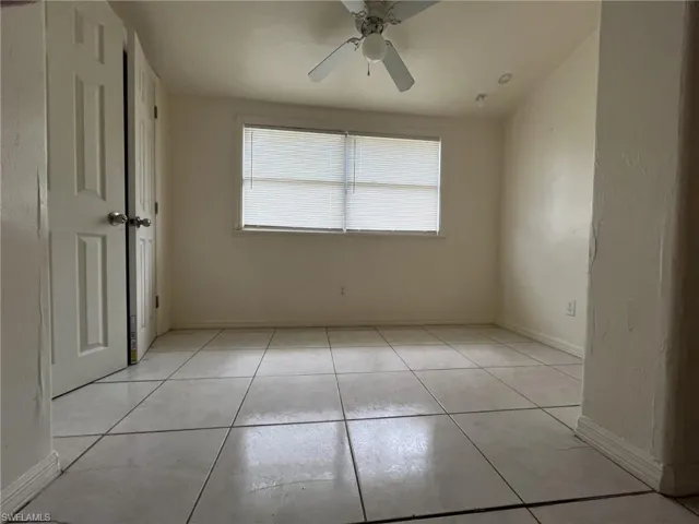Empty room featuring light tile patterned floors, a ceiling fan, and baseboards