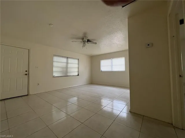 Empty room with light tile patterned flooring, a textured ceiling, and a ceiling fan