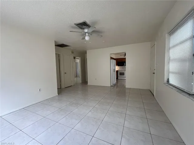 Unfurnished room featuring light tile patterned floors, visible vents, a textured ceiling, and a ceiling fan
