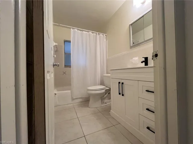 Bathroom featuring vanity, wainscoting, tile walls, toilet, and tile patterned floors