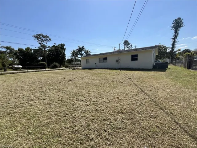 Back of property with stucco siding, a lawn, and fence